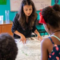 Founder of ISeeChange, Julia Kumari Drapkin, shows children a map of historic New Orleans. Drapkin highlights the parts of the city that used to be swamp. Credit: Impact Media Lab / AAAS