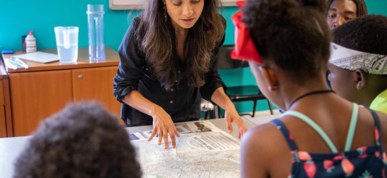 Founder of ISeeChange, Julia Kumari Drapkin, shows children a map of historic New Orleans. Drapkin highlights the parts of the city that used to be swamp. Credit: Impact Media Lab / AAAS