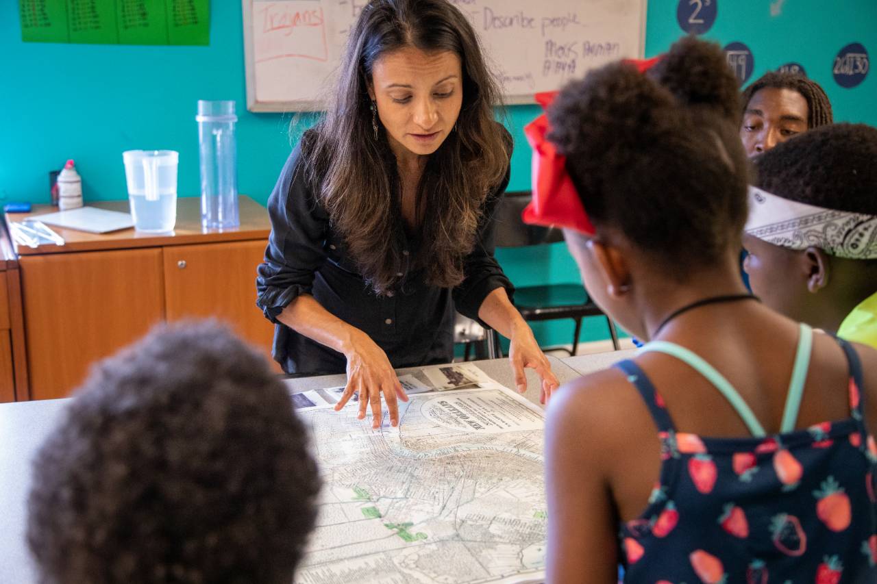 Founder of ISeeChange, Julia Kumari Drapkin, shows children a map of historic New Orleans. Drapkin highlights the parts of the city that used to be swamp. Credit: Impact Media Lab / AAAS